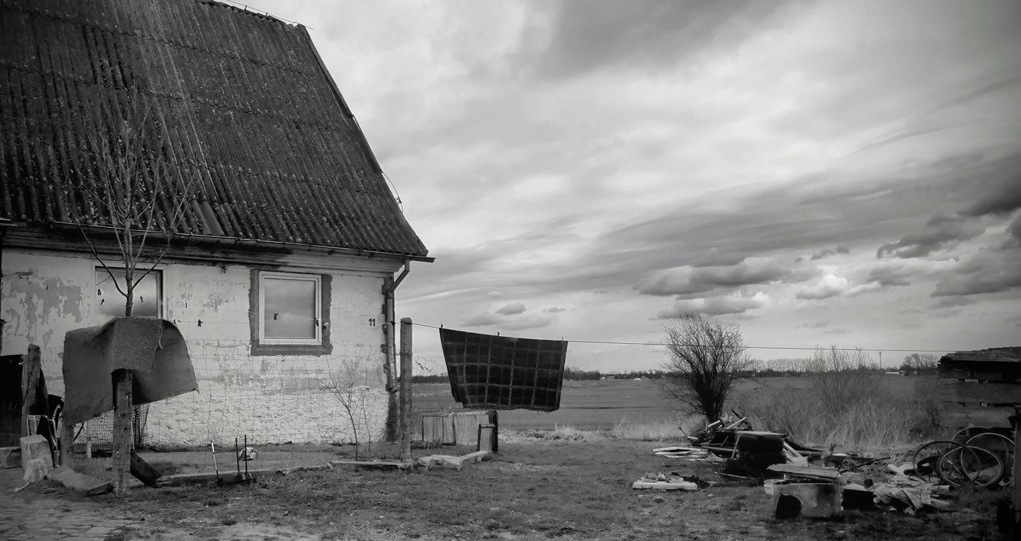 Czarno-białe zdjęcie starego wiejskiego domu na tle chmur
